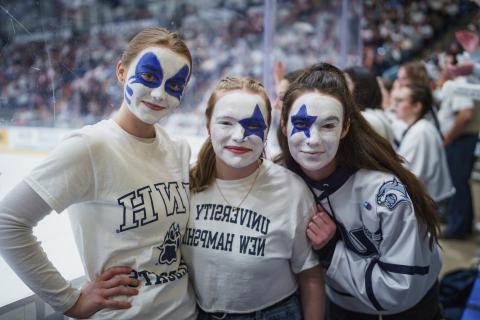 UNH students with spirit face paint at hockey game